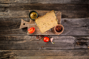 Traditional French Pate en croute with goose meat and liver as closeup on a wooden board. banner...
