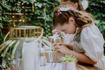 Little girls preparing gift for bride at wedding garden party.