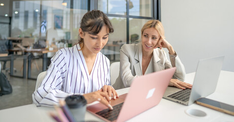 Businesswoman is working in office discussion with colleague using laptop computer and wireless technology. Modern woman and coworker teamwork meeting, brainstorming success business strategy.