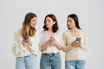 Three gorgeous brunette women posing at camera with cellphones