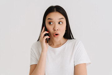 Asian surprised woman wearing t-shirt talking on mobile phone