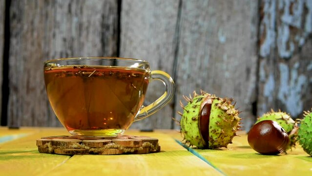 Tea in cups on the background of vintage boards. Chestnut brown tea in a transparent cup. Medicinal tincture from chestnut leaves. Healing infusion drink naturopathy