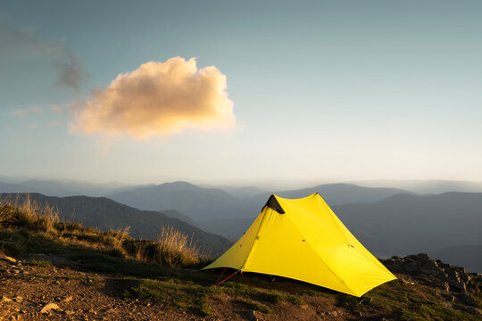 Yellow tent against the backdrop of an incredible mountain landscape during morning sunrise. Amazing highland. Tourism concept