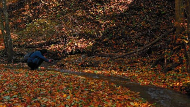 A man taking picture to the creek in the forest in autumn