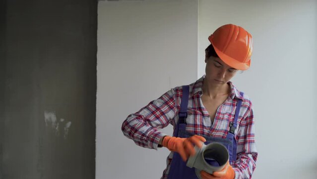 Plumber woman installing pvc sewer pipes at home or construction site