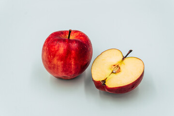 a whole and half cut red apple on white background