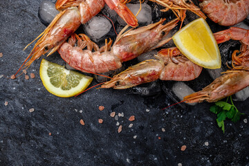 Red Argentine shrimps with ice and lemon, Wild shrimps, ocean jumbo shrimps on a dark background. Restaurant menu, dieting, cookbook recipe top view