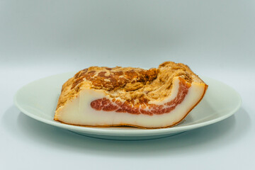traditional homemade smoked pork bacon on a white plate