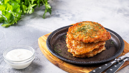 Tasty potato pancakes on a frying pan with sour cream