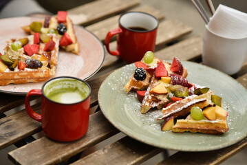 Belgian waffles with fruits and coffee on a wooden table in a cafe