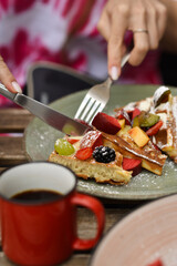 Woman eating Belgian waffle with fruits in cafe
