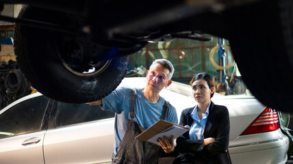 Asian young woman customer talking with owner and mechanic worker at car repair service and auto store shop.