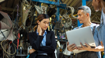 Serious asian young woman customer talking with owner and mechanic worker at car repair service and auto store shop.