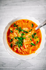 Chicken soup with noodles and vegetables in white bowl on wooden table background