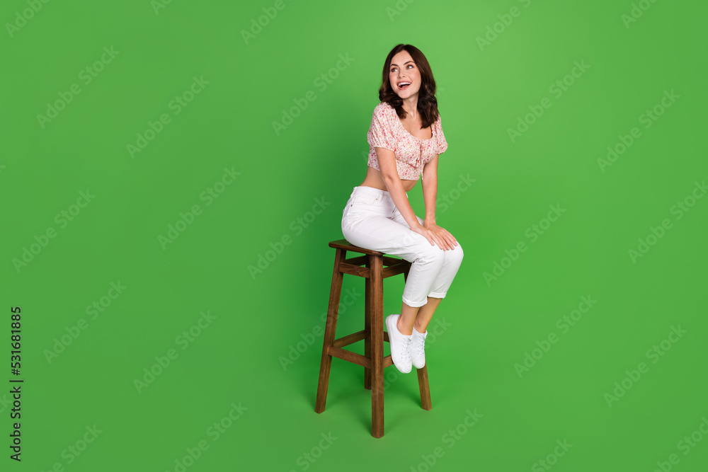 Wall mural Photo of funky dreamy lady wear print top sitting bar chair looking back empty space isolated green color background