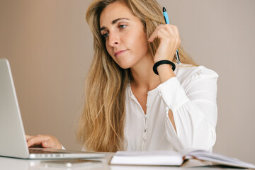 Woman writing in diary and using laptop on table