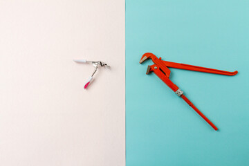 Top view contrast of mens and womens tools. Red adjustable wrench. White and turquoise surface.