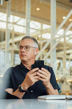 Businessman with diary on desk using smartphone in office