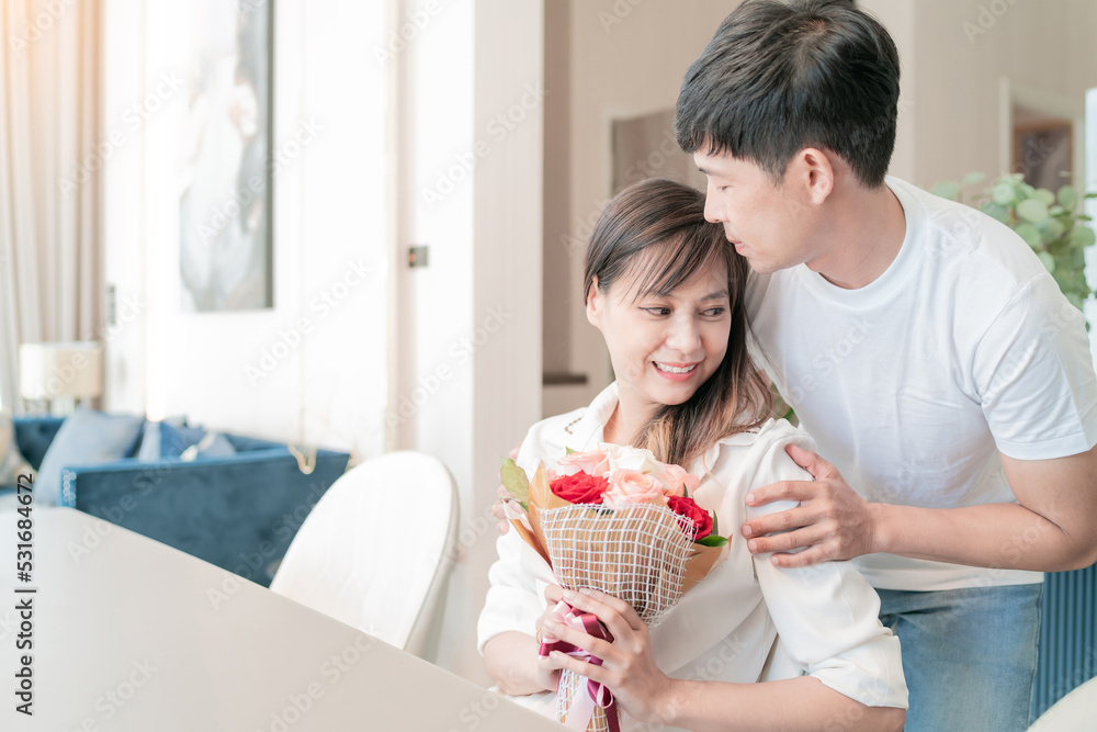 Wall mural handsome husband giving flowers to beautiful wife. happy family living together giving present. good relax man give gift for fun woman. lovely boyfriend surprised cute girlfriend with bouquet gift