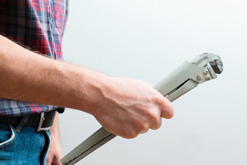 Workers hand and wrench. Close-up of plumber hands with wrench over plumbing tools background. Concept of repair and technical assistance.