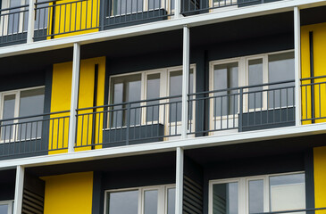 Fototapeta na wymiar the facade of a modern multi-storey building, windows and balconies, yellow and black walls, the concept of urbanism and city construction