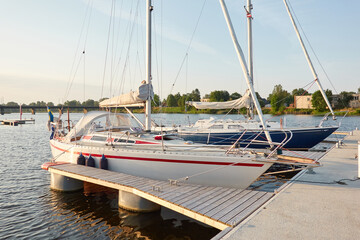 Sloop rigged sailboat (for rent and sale) moored to a pier in a yacht marina. Nautical vessel, transportation, amateur sailing, vacations, cruising, recreation concepts - 531687023