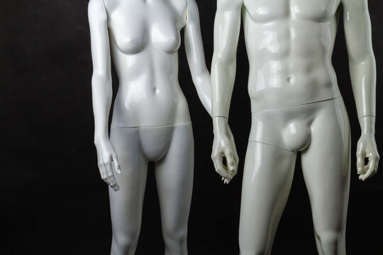 Holding hands of male and female mannequins. Isolated on black background.
