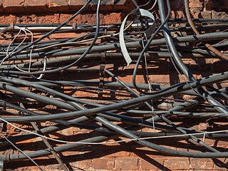 External telecommunication cables and wires randomly hanging on the brick wall