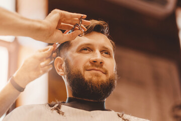 Obraz premium Barbershop concept, vintage color. Man haircut, master does hair styling