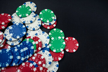 colored casino poker chips scattered on a black table.