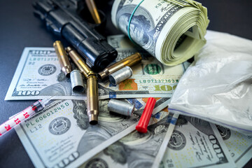 drug heroin lies next to syringes, money dollars weapons isolated on a dark background.