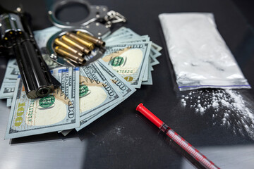 Drugs and money side gun with silencer and handcuffs isolated on black background.