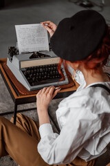 The girl prints on a typewriter. Creating a book. The writer is at work