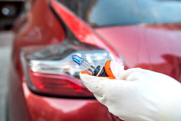 car lamp in a hand on the background of a car headlight.