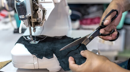 Close up hands using scissors cutting genuine leather in workshop, Leather business concept