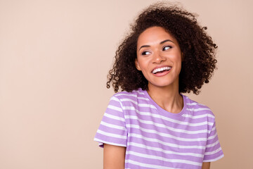 Photo of sweet thougthful girl dressed purple t-shirt looking empty space smiling isolated beige...