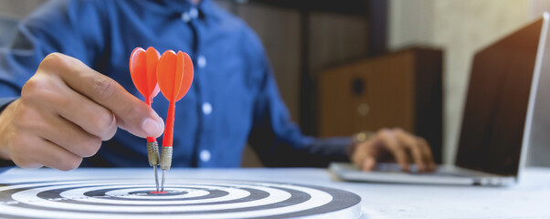 Businessman holding a darts aiming at the target center,business growth success concept.