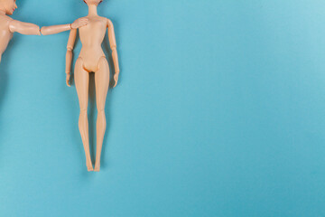 Back view naked doll man touching shoulder of woman. Blue surface and copy space.