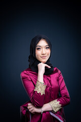 Closeup portrait of a beautiful female Muslim model wearing hijab, a lifestyle apparel for Muslim women isolated on dark grey background. Modern hijab fashion concept.