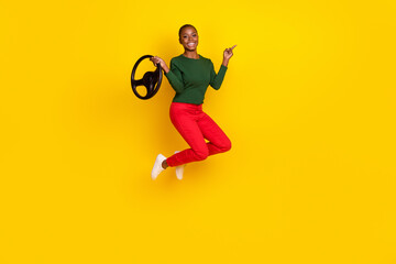 Fototapeta na wymiar Full length photo of funky positive lady dressed green shirt jumping high riding auto empty space isolated yellow color background