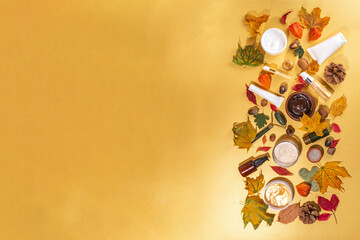 Set various nourishing moisturizing anti-aging autumn facial skin care cosmetics. Serum bottle, cream, scrub, organic beauty care with autumn leaves, decor, warm sweater, on golden yellow background