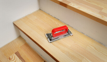 Closeup of sanding tool at wooden stairs, home renovation