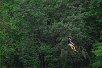 Zipline is an exciting adventure activity. Man hanging on a rope-way.