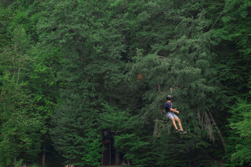 Zipline is an exciting adventure activity. Man hanging on a rope-way.
