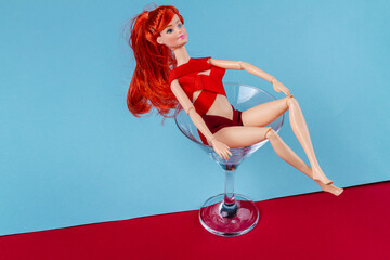 Sexy ginger doll bathing in martini glass. mannequin wrapped in red tape.