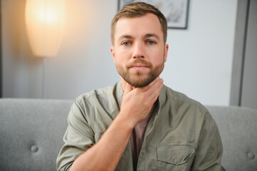 Sore throat. Dark-haired young man having a sore throat.