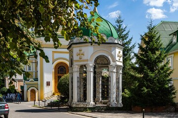 Orthodox church of Voronezh diocese. Green domes with golden Orthodox crosses against blue sky. Resurrection Church in city of Voronezh. Parishioners near entrance. Voronezh, Russia - July 30, 2022