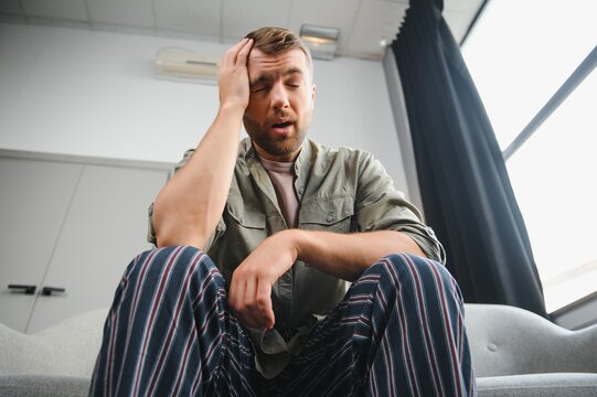 Ill Man Sitting On His Bed With His Head On His Hand