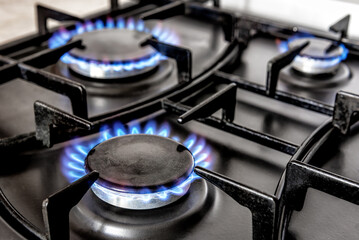 Three kitchen stove with blue gas flame