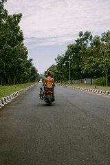 Surfer rides on motorbike with surfboard. Bali island, Indonesia. Young stylish man driving a scooter. Surfer with a surfboard on a rack on a motorcycle.